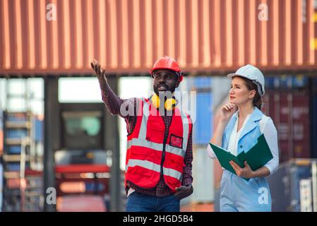 Femme d'affaires et ingénieur parlant et vérifiant le chargement de la boîte de conteneurs à partir du fret cargo navire pour l'importation exportation. Expédition dans les quais. Banque D'Images