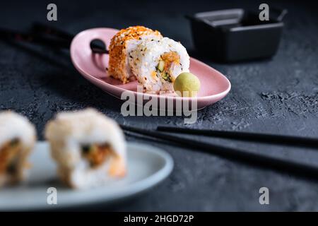 Divers petits pains à sushis sur fond sombre avec baguettes, wasabi et sauce soja.Cuisine traditionnelle japonaise de rue Banque D'Images