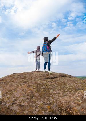 Les voyageurs père fille avec les mains levées marchant grimper sur le sommet de montagne appréciant la vue aérienne bleu ciel nuageux vue arrière ensemble.Lifest actif Banque D'Images
