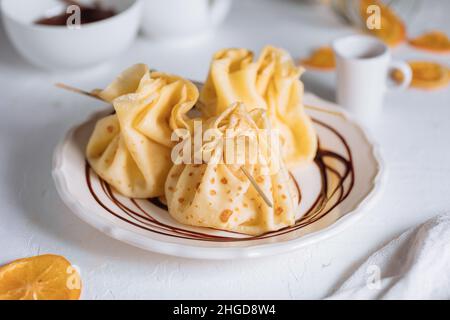 Crêpes crêpes crêpes formées en forme de pyramide sur une assiette bleue sur fond clair Banque D'Images