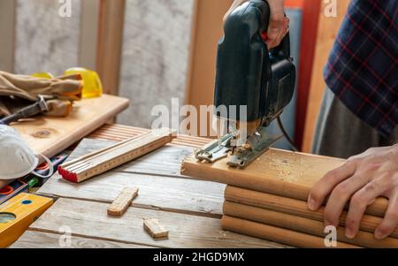 Scie sauteuse électrique, menuisier coupant le bois à la main avec une scie électrique.Industrie de la construction, table de travail vue rapprochée Banque D'Images