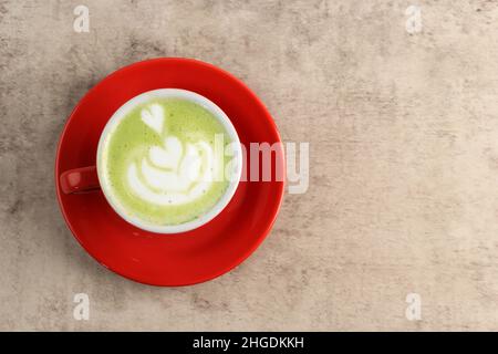 Macha latte greentea Foam Art est coeur dans une coupe rouge, sur rustique Vintage Table Copy espace pour le texte et la publicité Banque D'Images