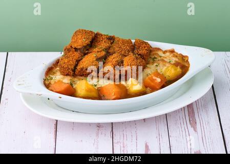 Pâtes chaudes japonaises cuites au four Chesy Shroom Curry ingrédient - oignon, poulet, pomme de terre, carotte, curry et fromage dans un bol blanc sur table de nourriture en bois Banque D'Images