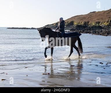 Silhouette de femme à cheval à travers les vagues sur la plage.West Cork Irlande Banque D'Images