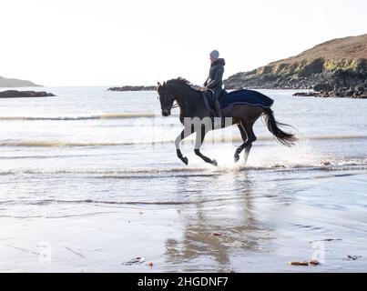 Silhouette de femme à cheval à travers les vagues sur la plage.West Cork Irlande Banque D'Images