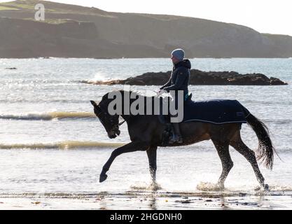 Silhouette de femme à cheval à travers les vagues sur la plage.West Cork Irlande Banque D'Images