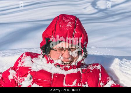 Le visage d'un homme dans la neige, qui s'amuse en hiver dans la forêt en sautant dans une dérive de neige.Visage gelé d'un homme avec un sourire Banque D'Images
