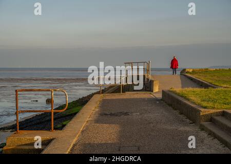 Femme séjournant sur le mur de la mer à grain, Isle Off grain, Kent.En regardant vers la Sheerness Banque D'Images