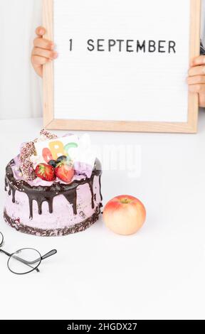 Gâteau de fête avec ABC, pomme, verres.Retour à l'école.Bonjour école.Le temps d'apprendre.Éducation.Mains d'enfant tenant le tableau de lettres avec texte 1 septembre.C Banque D'Images