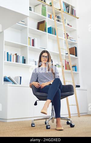 Portrait d'une jeune femme portant des lunettes devant les étagères à la maison Banque D'Images