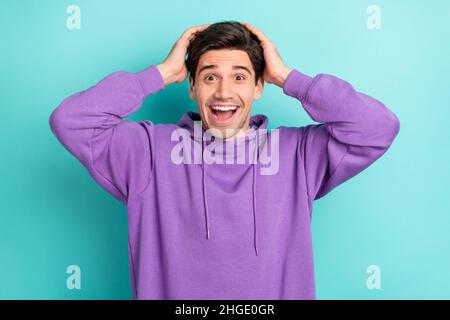 Photo d'un jeune gars branché choqué habillé violet sweat-shirt bras tête ouverte bouche souriante isolé couleur turquoise fond Banque D'Images