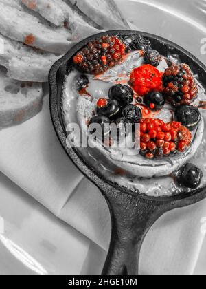 Baies de couleur sélective avec yaourt servies dans une petite poêle en fonte Banque D'Images