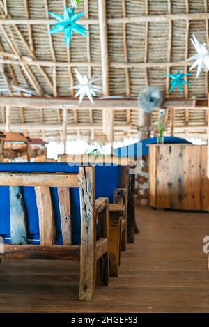 Tables en bois dans un café sous un toit.Intérieur authentique du restaurant à Kendwa, Zanzibar, Tanzanie. Banque D'Images