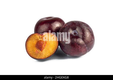 Prunes entières et à moitié mûres isolées sur fond blanc.Prunes de cerise pourpre naturelles et biologiques.Partie de l'ensemble. Banque D'Images