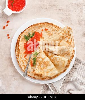 Crêpes, crêpes fines, crêpes russes avec caviar rouge sur une assiette grise. Arrière-plan en marbre. Copier l'espace. Vue de dessus. Banque D'Images