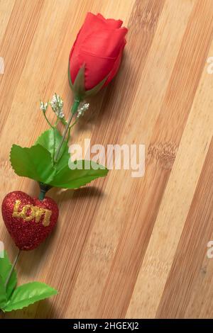 Le fond de la Saint-Valentin avec des roses en plastique rouge sur une table en bois pour le concept de l'amour. Banque D'Images