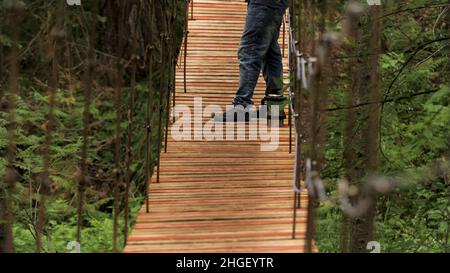 Vue latérale d'un homme se tenant sur le pont suspendu en bois et fumant un tuyau tout en regardant au loin.Randonneur ayant un repos et appréciant l'été FO Banque D'Images