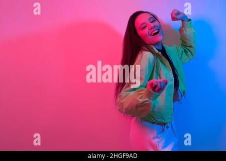 La brunette danse au néon, la danseuse en rouge-bleu.Hip hop fille, fête, sourire. Banque D'Images