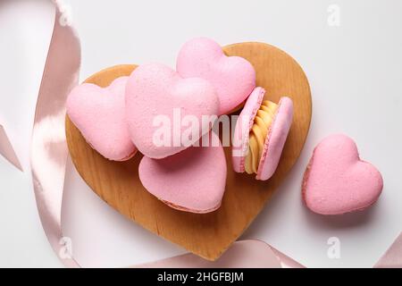 Embarquez avec de savoureux macarons en forme de cœur sur fond blanc Banque D'Images