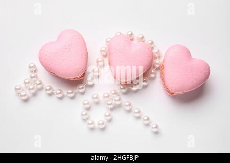 Macarons et perles en forme de cœur savoureux sur fond blanc Banque D'Images