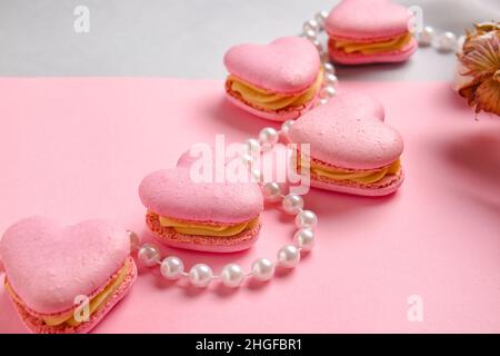 Macarons et perles en forme de cœur savoureux sur fond de couleur, gros plan Banque D'Images