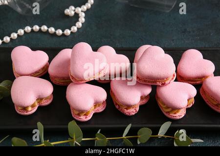 Embarquez avec de savoureux macarons en forme de cœur sur fond noir Banque D'Images