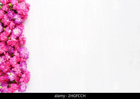 Les fleurs d'œillets roses bordent un fond en bois blanc.Concept de la Fête des mères, de la Saint-Valentin.Vue de dessus, espace de copie Banque D'Images