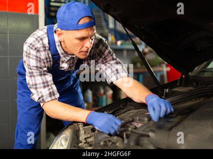 Homme positif mécanician de voiture de réparation de voiture dans le service de réparation d'auto Banque D'Images