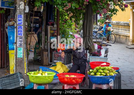 Une femme vietnamienne se trouve dans un coin où elle vend ses produits dans la vieille ville. Banque D'Images