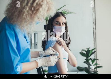 Médecin utilisant un coton-tige avec de l'alcool pour nettoyer le bras de la femme avant d'appliquer un vaccin.Vaccination contre le coronavirus.Protection contre les virus.Main du médecin. Banque D'Images