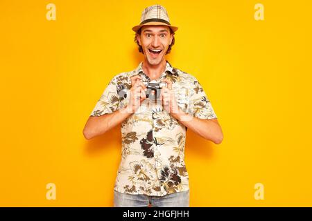 un voyageur de tourisme de sexe masculin excités avec sa bouche ouverte tient une caméra dans ses mains en face de lui. Banque D'Images