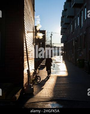 Une personne en silhouette marchant dans le quartier du Vieux Port de Portland, Maine. Banque D'Images