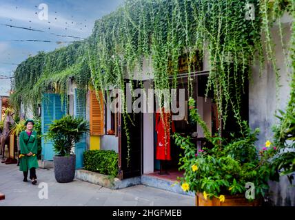 Un employé marche devant une boutique de soie à Hoi an Memories Resort. Banque D'Images