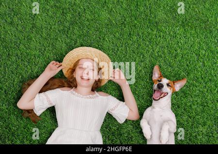 Petite fille riante et chien mignon Profitez de la journée d'été sur l'herbe dans le parc.Printemps, Pâques.Vue de dessus portrait. Banque D'Images