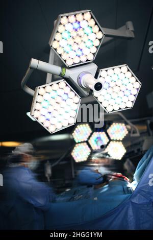 Chirurgiens travaillant sous la lampe sans ombre dans la salle de chirurgie. Banque D'Images
