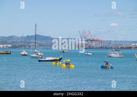 Tauranga Nouvelle-Zélande - janvier 17 2022 ; les amateurs de plage apprécient la journée d'été sur le front de mer et dans l'eau à Pilot Bay avec fond de port. Banque D'Images