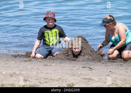 Tauranga Nouvelle-Zélande - janvier 17 2022;Beach-goers appréciant la journée d'été sur le front de mer achetant un garçon dans le sable à Pilot Bay Banque D'Images