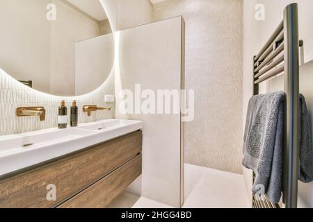 Salle de bains élégante avec grand miroir rond éclairé et deux lavabos Banque D'Images