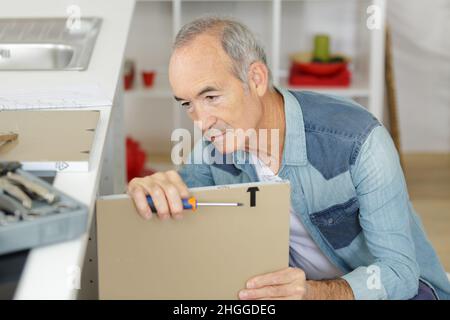 un homme âgé assemble des meubles Banque D'Images