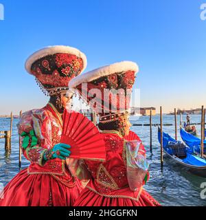 Deux femmes dans la belle historique rouge déguisements et chapeaux posent près de la lagune, carnaval de Venise, Carnevale di Venezia, Vénétie, Italie Banque D'Images