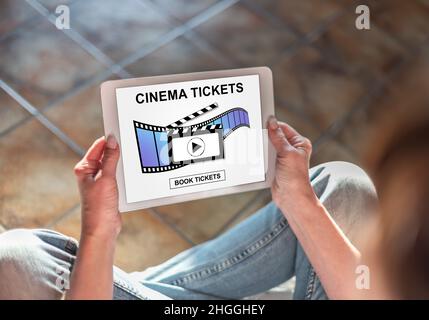 Femme assise sur le sol avec une tablette montrant le concept de réservation de billets de cinéma en ligne Banque D'Images