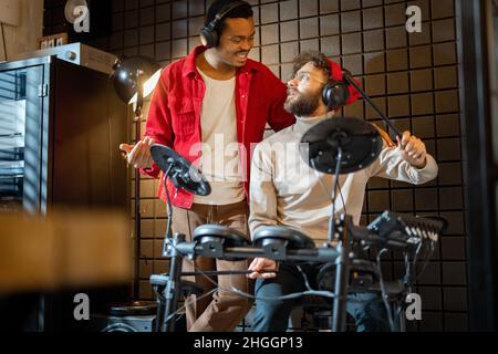 Hommes jouant des tambours électriques à la maison sstudio Banque D'Images