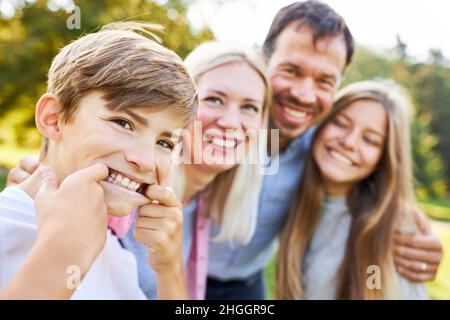 Garçon fait des grimaces drôles avec ses parents et sa sœur en été dans le parc Banque D'Images