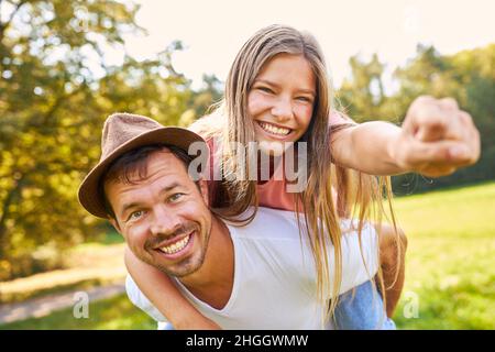 La fille aime être pigeybacked sur le dos du père dans la nature Banque D'Images