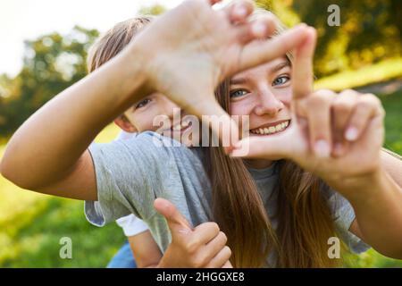 Frère et sœur forment une place avec leurs mains tout en jouant dans la nature Banque D'Images