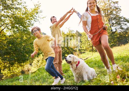 Frères et sœurs enfants jouant avec les parents et le chien dans le parc sur un pré Banque D'Images