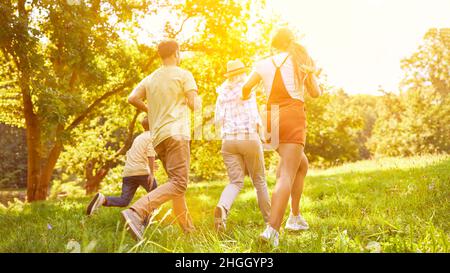 Vue arrière de la famille avec deux enfants qui s'exécutent dans le jardin en été Banque D'Images
