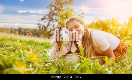 En été, une fille heureuse se câlin avec son chien dans le jardin Banque D'Images