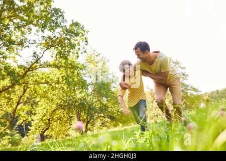 Père et fils s'amusent ensemble à lutter dans le parc en été dans la nature Banque D'Images
