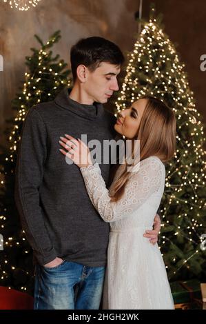 Un gars et une fille embrassent et embrassent contre le fond d'un arbre de Noël et d'un canapé rouge Banque D'Images